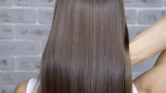 Result after lamination and hair straightening in a beauty salon for a girl with brown hair. hair care concept.