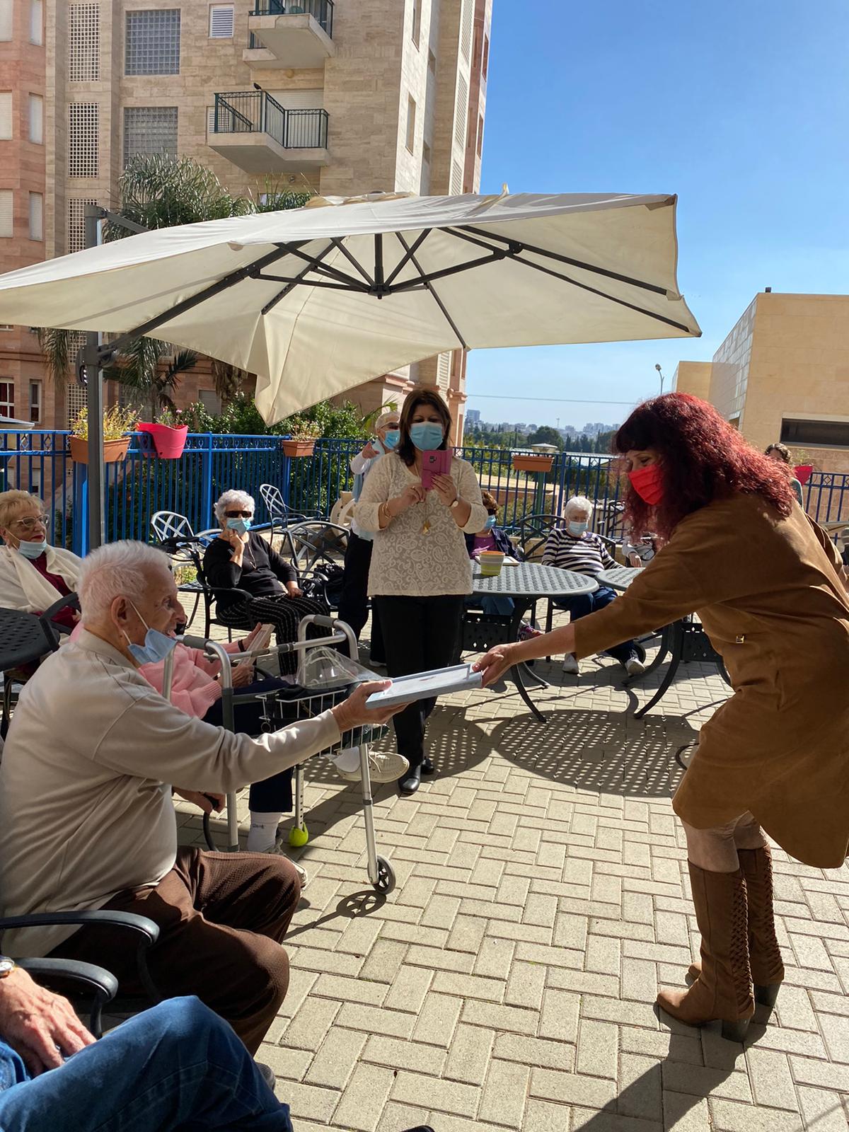 המנהלת מעניקה תעודת הוקרה לאחד התורמים